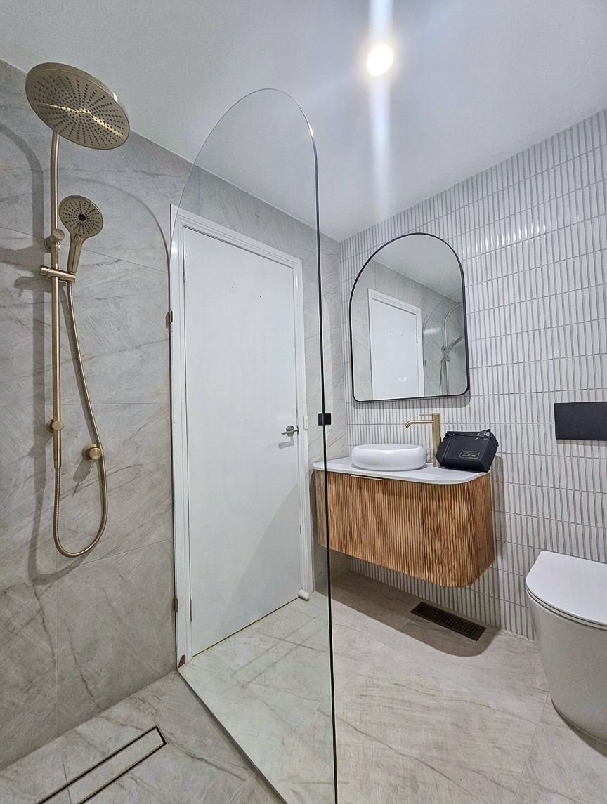 Bathroom renovation in Melbourne with an arched glass shower screen and fluted timber vanity