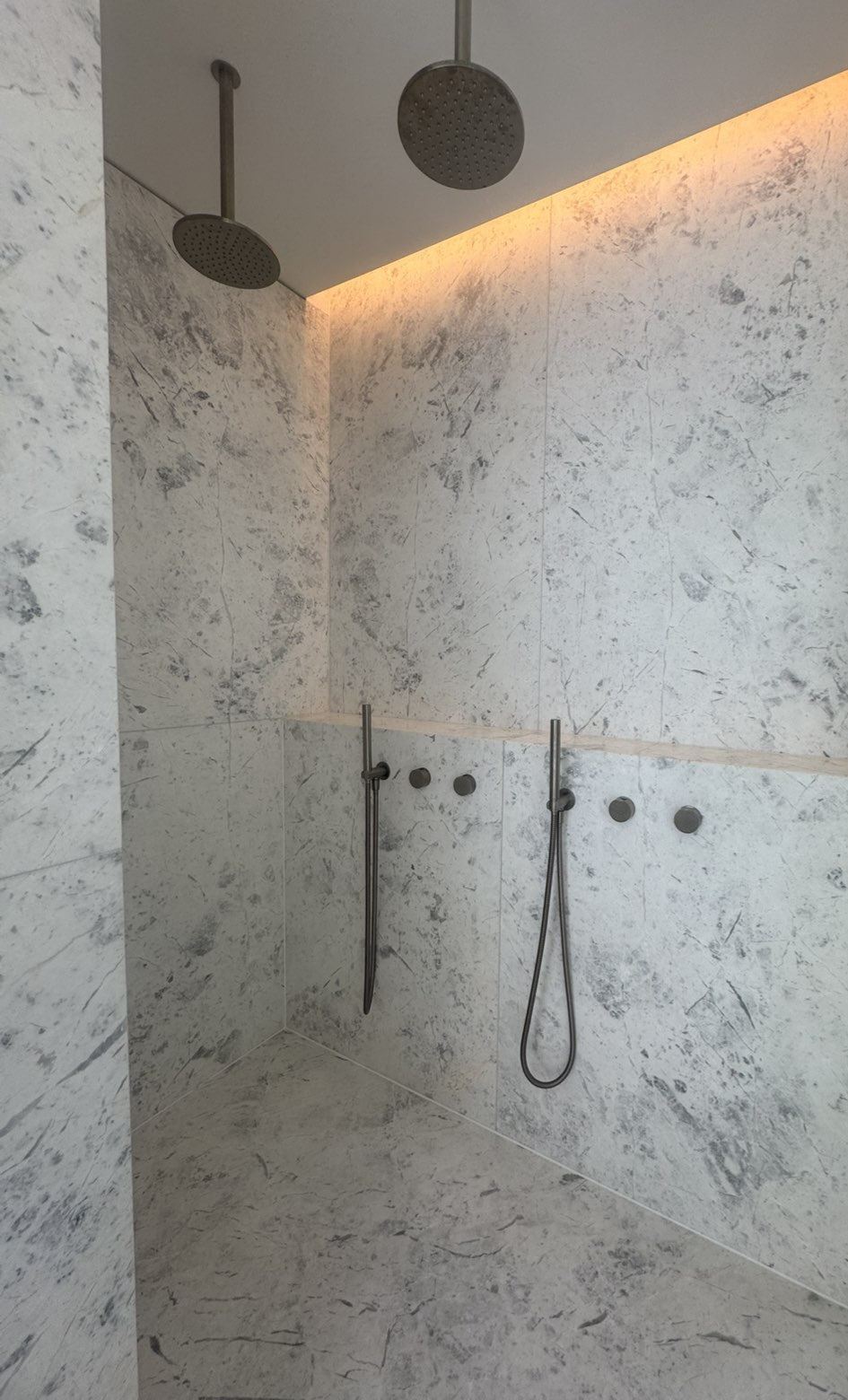 Bathroom renovation in Melbourne with twin rain shower heads and backlit marble-look tile